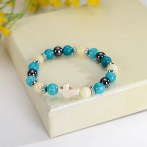 Gros plan d'un bracelet en perles de 8mm avec pierres naturelles et pendentif croix crème