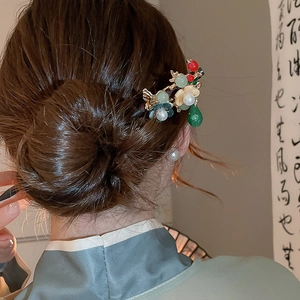 Close-up of Chinese tassel hair pin with floral motifs and pearls on an elegant updo