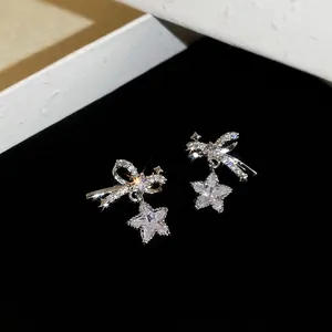 Elegant silver bow and star drop earrings with cubic zirconia on black velvet background