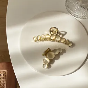 Elegant gold alloy hair claws set with opal stones shown in large and small sizes