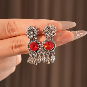 Detail of vintage silver flower earrings with red stones and small metal bells