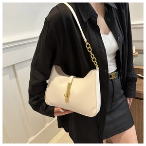Close-up of cream leather shoulder bag with gold chain strap and vertical metal buckle