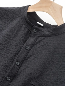 Macro detail of black polyester polo shirt with seersucker texture and buttoned collar