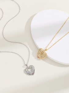 Detail of silver and gold swan heart necklaces with pink gemstone on stone display