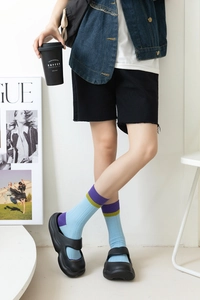 Close-up of light blue striped crew socks with purple and green contrast ribbed cuffs