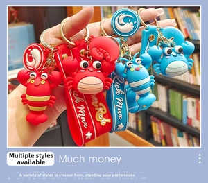 Close-up of cute lobster and crab keychains with Rich Man wrist strap in hand