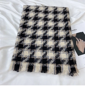 Detailed view of houndstooth scarf texture with fringed edges on a soft white background
