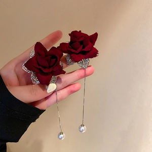 Dettaglio dell'orecchino rosa bordeaux con foglia argentata e pendente con perla