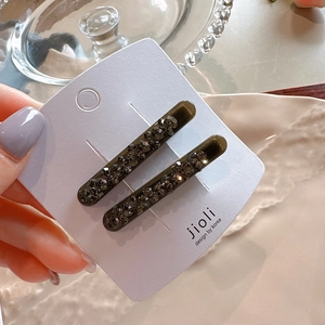 Detail of dark green hair clips with sparkling rhinestones on a display card