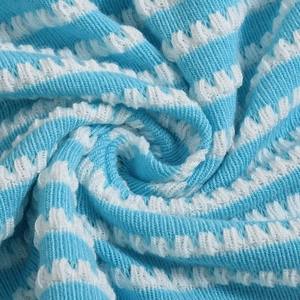 Close-up of blue and white striped knit fabric with a dimensional spiral texture