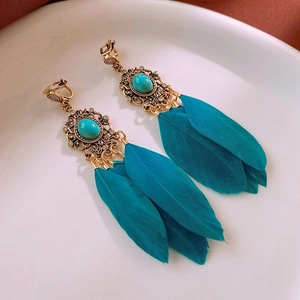 Vue détaillée de boucles d'oreilles vintage en or avec turquoise et plumes bleu paon