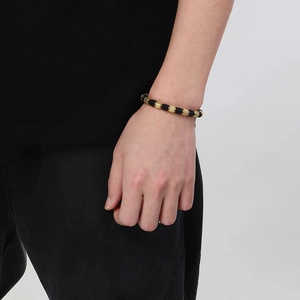 Men's black and gold woven bracelet with textured stainless steel beads on wrist