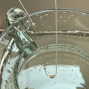 Detailed macro view of 925 sterling silver beaded snake chain on glass with water droplets