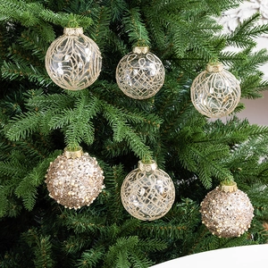 Hanging gold and transparent Christmas balls with intricate patterns on a tree