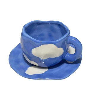 Hand-pinched irregular ceramic coffee cup and saucer with blue sky and white cloud pattern