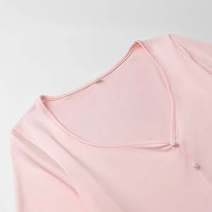 Detail view of pink V-neck knit dress with matching fabric-covered buttons and fine texture