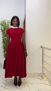 Detalle de vestido largo rojo de talle alto con cuello mao blanco y falda plisada
