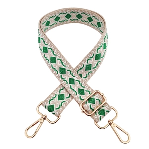 Detail of green diamond pattern woven bag strap with golden metal snap hooks and buckles