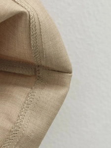 Detailed view of beige woven fabric texture and high-quality stitching on a sleeveless dress