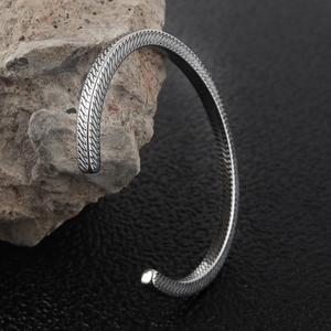Silver diamond-patterned stainless steel cuff bracelet on natural stone display