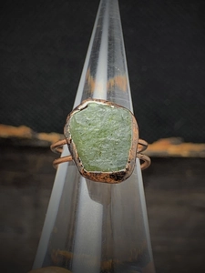 Detailed close-up of a vintage adjustable ring with a raw green gemstone on a metal band