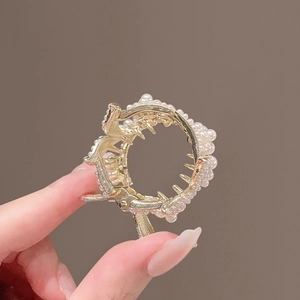 Gros plan d'une pince à cheveux dorée ornée de perles élégantes et de dents de peigne internes