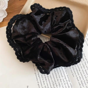 Detailed view of black velvet scrunchie with knitted trim on a vintage book