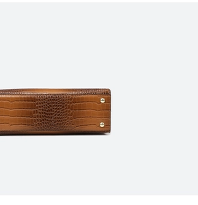 Detail view of brown crocodile embossed leather bottom with gold protective metal studs