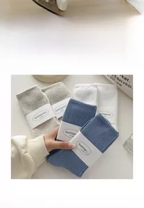 Close-up of ribbed knit cotton crew socks in blue and beige with delicate paper labels