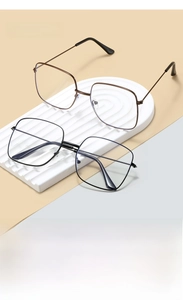 Detail of square oversized metal glasses frames in black and bronze on a wavy display