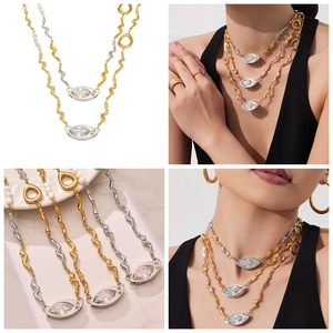 Detail view of gold and silver irregular chain necklace with pearl and eye pendant