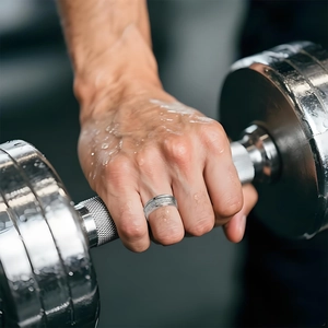 Men's retro punk skull titanium ring shown with dumbbell in a high-intensity gym workout