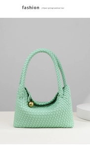 Detail of mint green woven tote bag with smooth texture and golden metal ball charm