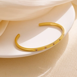 Detailed view of matte 18k gold plated cuff bracelet with pink zircon stone inlay