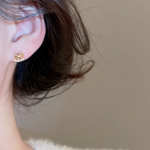 Gros plan d'un clou d'oreille poney plaqué or avec zircons étincelants sur l'oreille