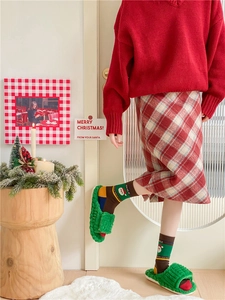 Detailed view of Christmas themed cotton socks and green plush slippers in festive home setting