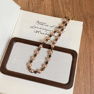 Vintage tiger eye and champagne pearl necklace with gold accents on antique book
