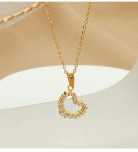 Macro shot of gold heart pendant necklace with shimmering zircon stones on a white stand