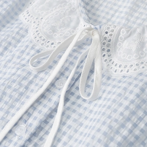 Detail of white lace collar and bow tie on blue plaid cotton blouse for women