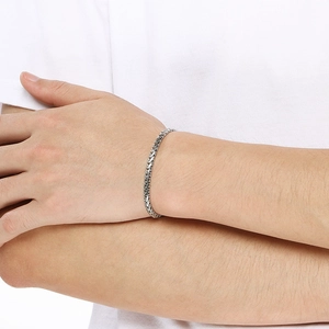Gros plan d'un bracelet en maille épi en acier inoxydable poli porté au poignet