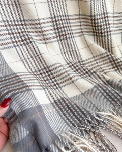 Detailed close-up of beige and gray plaid scarf featuring soft knit texture and tassels