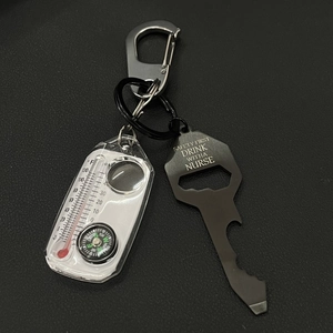 Detail of multi-functional black metal bottle opener with compass and thermometer tool