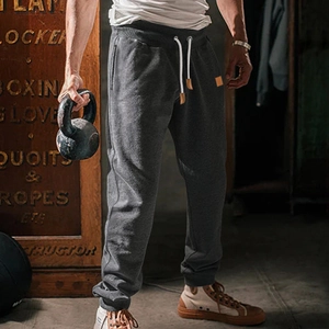 Detail of dark grey jogger pants showing drawstring waist and pockets in a gym setting