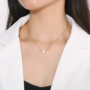 Close-up of a delicate 18K gold-plated necklace with a single white shell pearl pendant