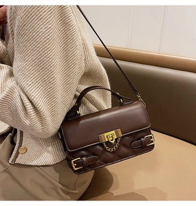 Detail of a brown leather quilted bag with gold hardware and chain strap on a model