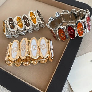 Detail view of retro elastic bracelets with enamel oil drip patterns in a jewelry tray