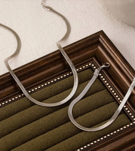 Polished silver herringbone snake chain necklace with lobster clasp on velvet display