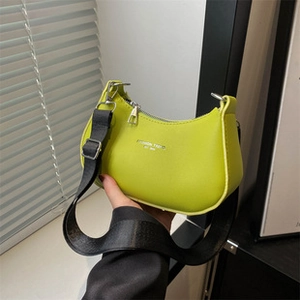 Detail of lime green small square bag with black fabric strap and silver hardware accents