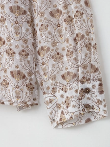 Détail de la manche en mousseline fleurie avec boutons marron et tissu floqué