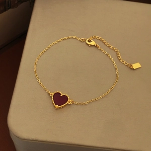 Detail of gold-plated chain bracelet with red heart pendant and beaded edges